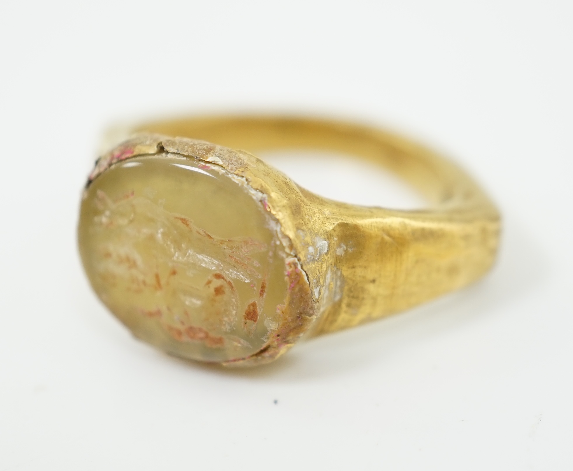 A Roman gold and hardstone intaglio military finger ring, carved with Saturn beside a pedestal